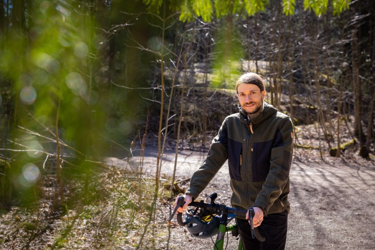 Jussi-Pekka Teini taluttaa pyöräänsä metsätiellä.