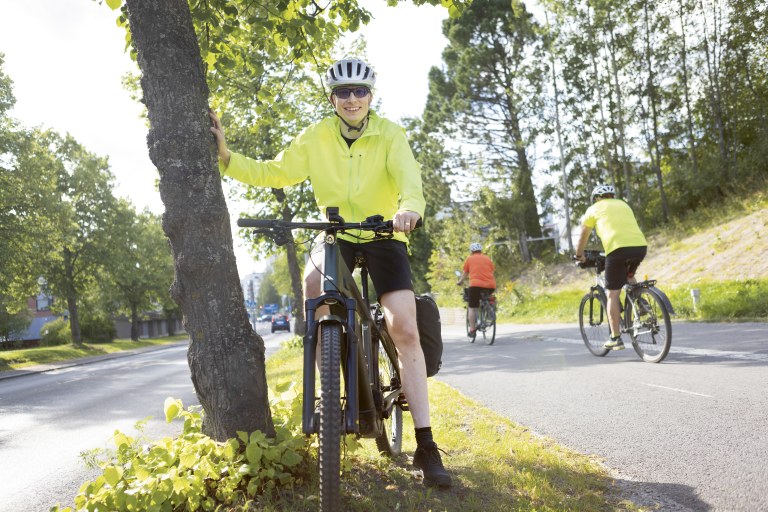 Juho Väisänen nojaa pyöränsä selässä puuhun.