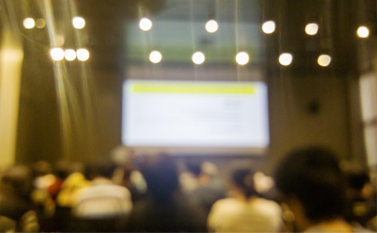 A lecture in an auditorium with bright lights.