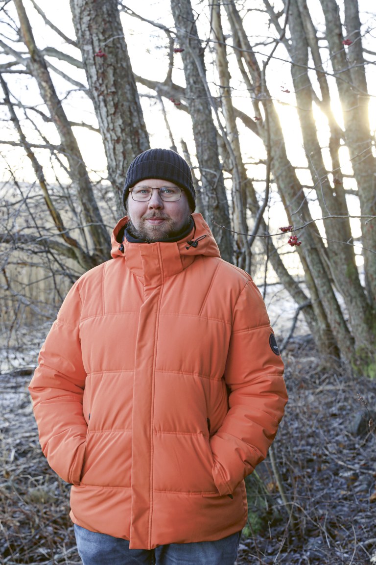 Henry Schwartz seisoo kädet takkinsa taskuissa ja katsoo kameraan.