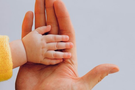 Two hands: one is an adult hand and the other a hand of a baby.