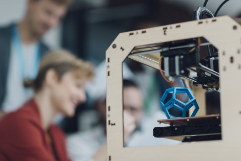 Edessä 3D-printteri, takana tiimi.