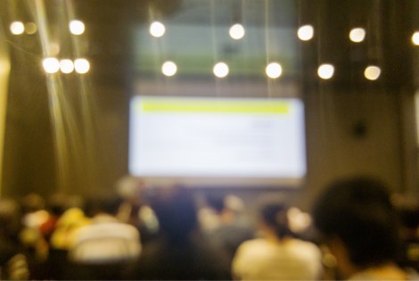 A lecture in an auditorium with bright lights.